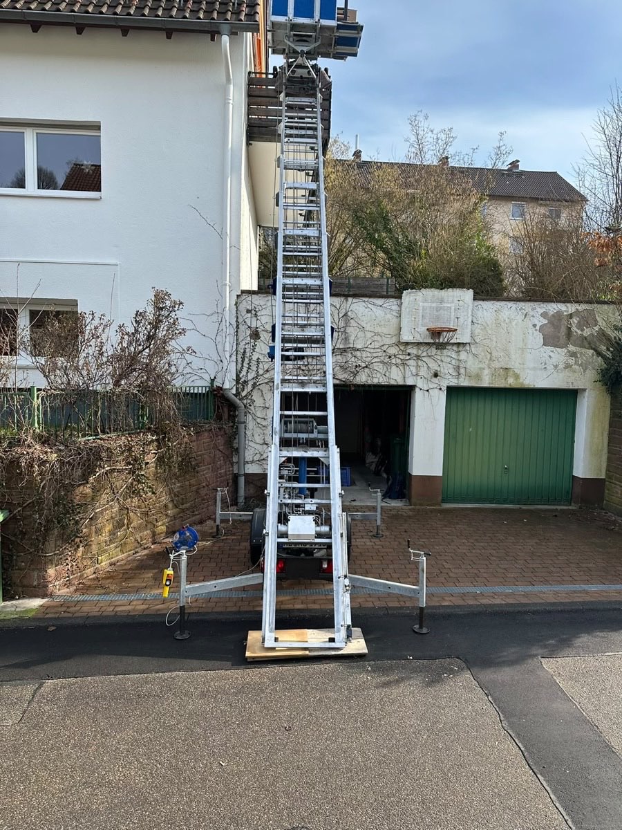 Aufgebauter Möbellift von MO Umzüge reicht bis unter das Dach eines Wohnhauses